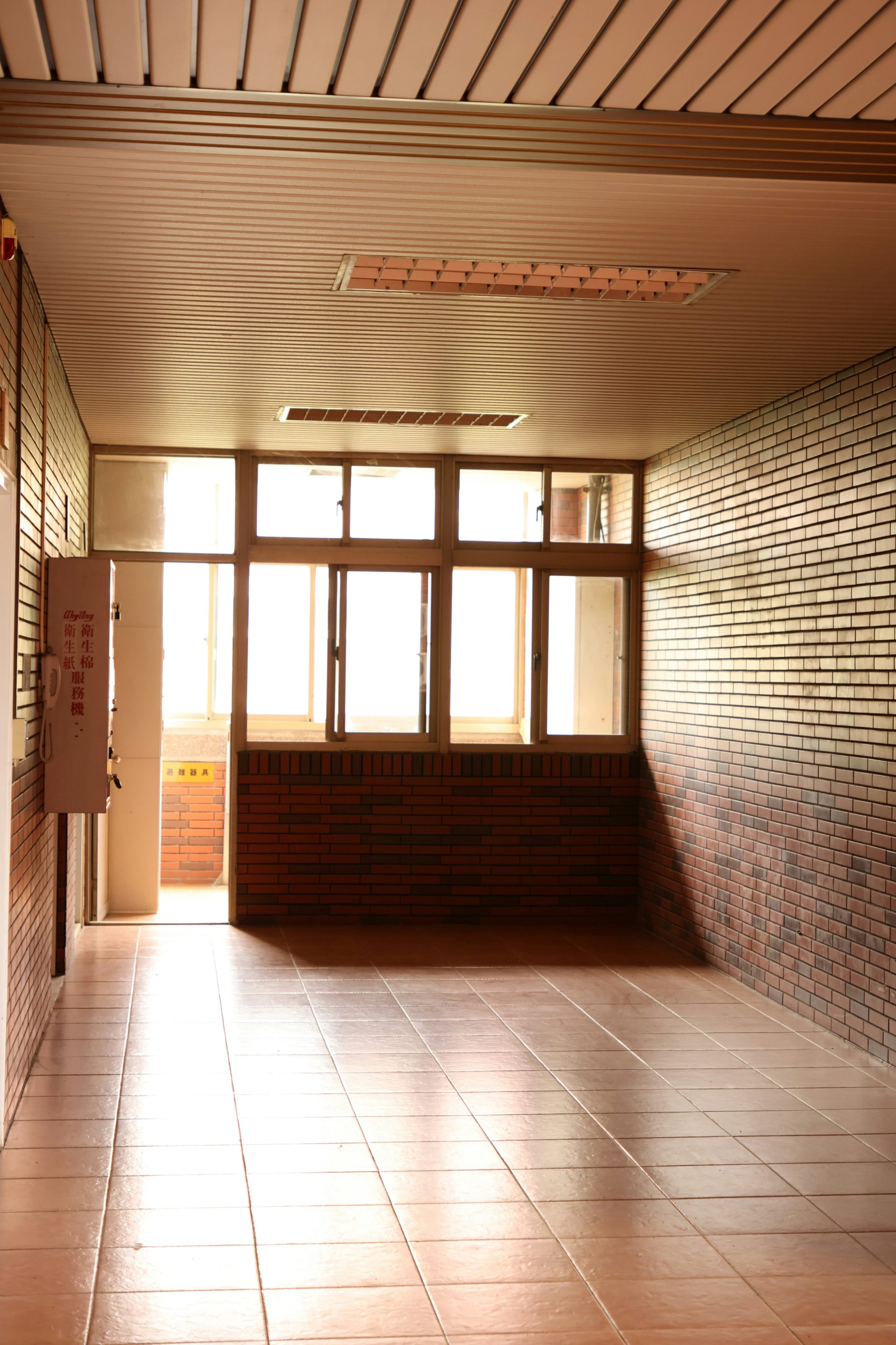 Couloir baigné de lumière naturelle avec sol carrelé et murs en briques